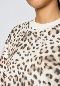 T-shirt με λεοπάρ σχέδιο σε μπεζ και καφέ αποχρώσεις, με κοντά μανίκια και λαιμόκοψη ριπ, με το λογότυπο "STRONGER" σε ασημί κέντημα.