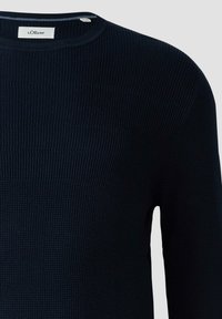 Granatowa koszula z długim rękawem o teksturowanym prążkowanym wzorze. Posiada okrągły dekolt oraz małą metkę marki umieszczoną na kołnierzu.