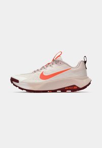 Nike trail running shoe with a breathable light beige mesh upper, bright orange swoosh, red outsole, and reflective accents.