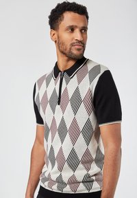 Pikeepaita lyhythihaisena, jossa on harmaa, musta ja viininpunainen rombikuvio, musta kaulus ja vetoketjuyksityiskohta.