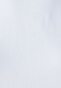 Tejido de algodón blanco con una textura de estría fina. Presenta una pequeña etiqueta triangular en el escote, que indica la marca o el tamaño.