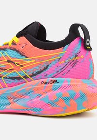 Talons de chaussures de course rose vif, orange et bleu avec un col noir, des lacets jaunes et marqué "GEL-NIMBUS" et "PureGEL" sur la semelle intermédiaire.