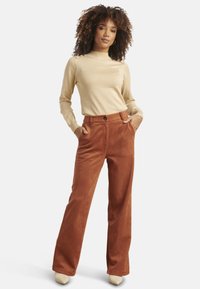 Tan long-sleeve top paired with rust-colored wide-leg pants made of soft fabric, featuring a button closure and side pockets.