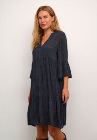 Abito blu navy con scollatura a V, maniche a campana tre quarti e design a strati. Presenta un sottile motivo botanico in una tonalità più chiara.