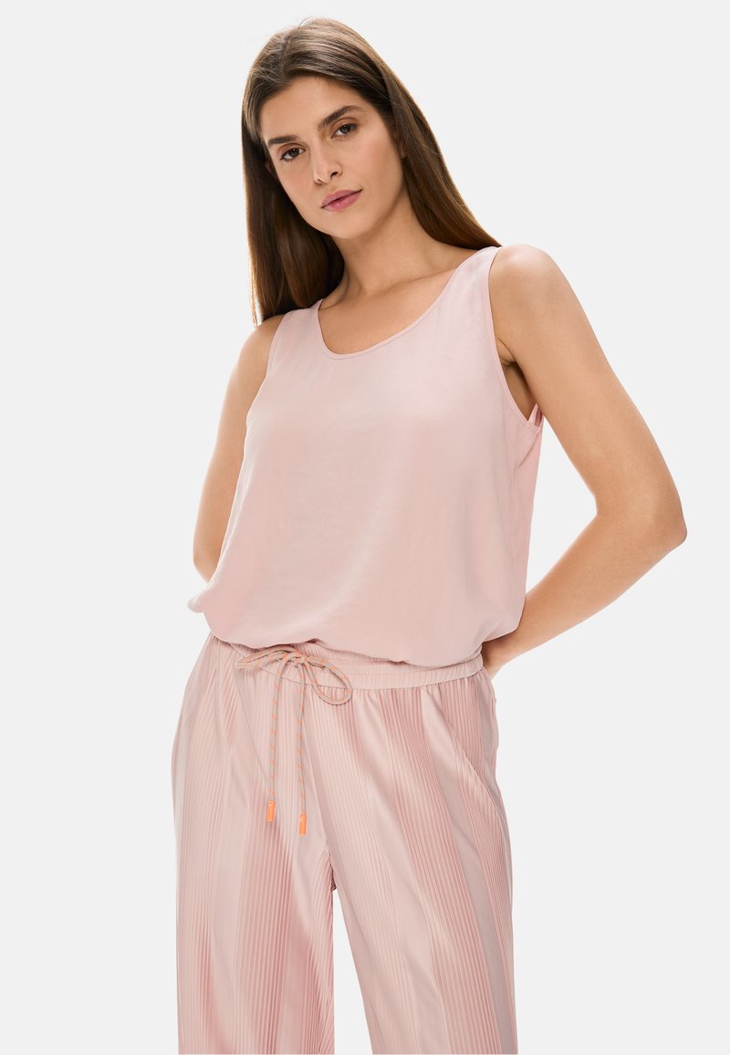 Light pink sleeveless top with a smooth texture and rounded neckline, paired with light pink pleated pants featuring drawstring and orange accents.