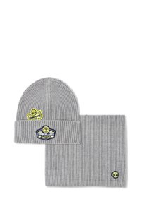 Ensemble bonnet et écharpe en tricot gris, avec une texture côtelée et des logos Timberland en jaune et bleu. Les accents incluent des étiquettes de marque.