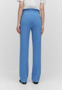 Ljusblå vida byxor med en slät yta, med en mid-rise midja och två bakfickor. Siluetten är skräddarsydd och avslappnad.
