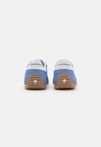 Tenisi bleumarin din piele întoarsă cu accente albe, având un detaliu în formă de stea pe călcâi și o talpă din cauciuc. Logo-ul Converse este vizibil pe spate.