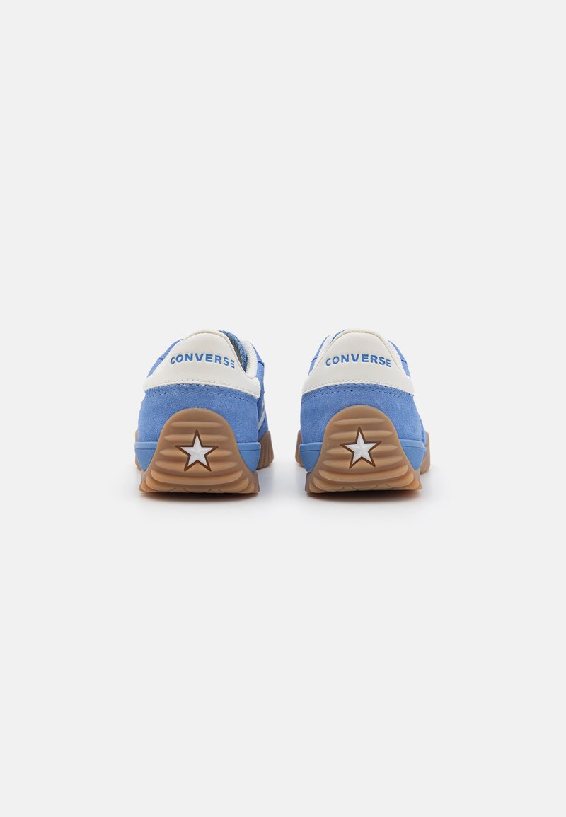 Blaue Wildledersneaker mit weißen Akzenten, ausgestattet mit einem Sternmotiv an der Ferse und einer Gummisohle. Converse-Logo auf der Rückseite sichtbar.