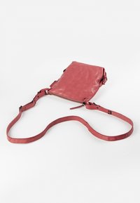 Rote Leder-Crossbody-Tasche mit glatter Textur, Reißverschluss, verstellbarem Riemen und minimalistischen Design. Mit schwarzem Zubehör akzentuiert.