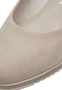 Chaussure plate en daim beige avec bout arrondi et semelle intérieure rembourrée, dotée d'une semelle en caoutchouc avec légère rainure pour l'adhérence.