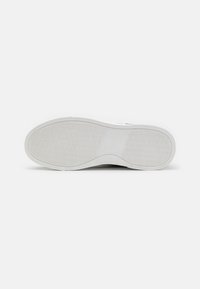 Suela de goma blanca con un patrón texturizado; bordes suaves; tacón redondeado; diseñada para ofrecer tracción y comodidad en diversos entornos.
