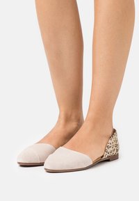 Bailarinas de ante beige con punta puntiaguda y tacón de leopardo. Textura suave con un diseño contrastante, que presenta un dorso abierto y un perfil bajo.