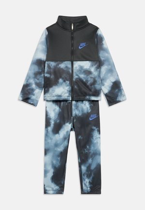 Nike trainingspak in zwart met blauwe wolkenprint. Bevat een ritssluitingjack met hoge kraag en bijpassende broek, beide met logo-accenten.