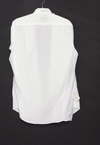 Camisa blanca de manga larga colgada en una percha sobre un fondo negro, con la etiqueta de la marca GANT visible en el cuello y la espalda.