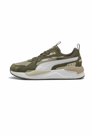 Baskets Puma vert olive et beige avec bande logo blanche, lacets à l’avant, languettes sur la languette et le talon, et semelle épaisse et rembourrée.