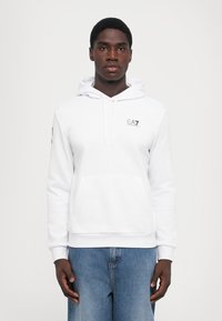 Sweatshirt branca com um bolso canguru, capuz ajustável com cordão e logótipo EA7 no peito. Fabricado em tecido de algodão suave, com um corte descontraído.