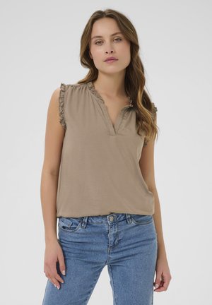 Beige mouwloze top met een gerimpelde halslijn en een knoopsluiting, gemaakt van zachte stof, gecombineerd met blauwe denim jeans.