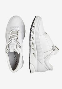 Weiße Sportschuhe mit Mesh-Details, strukturiertem Leder und Schnürdesign. Sie verfügen über eine schwarze Gummisohle mit Aussparungen zur Belüftung.
