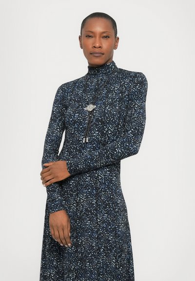 Long-sleeve black dress with a high neck, featuring a blue and white speckled pattern. Accented with a silver necklace.