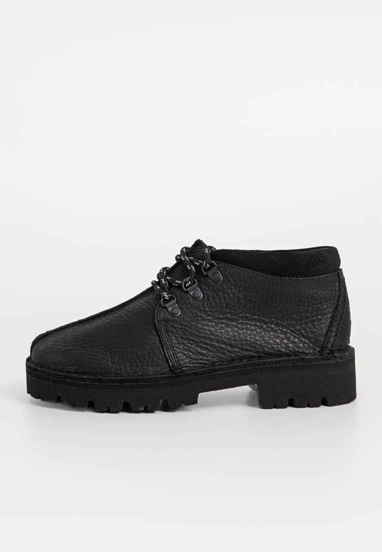 Bottines noires à lacets avec une tige en cuir texturé, semelle en caoutchouc robuste et œillets en métal. Présente un bout arrondi et un minimalisme dans les détails.