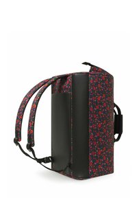 Sac à dos noir à motifs floraux, de forme rectangulaire, présentant des motifs de fleurs colorées sur le tissu et des accents en cuir noir. Bretelles réglables.