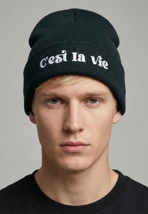 Gestrickte schwarze Mütze mit weißer eingestickter Aufschrift "C'est la Vie." Eng anliegendes Design, strukturierter Stoff. Einfacher, funktionaler Stil.