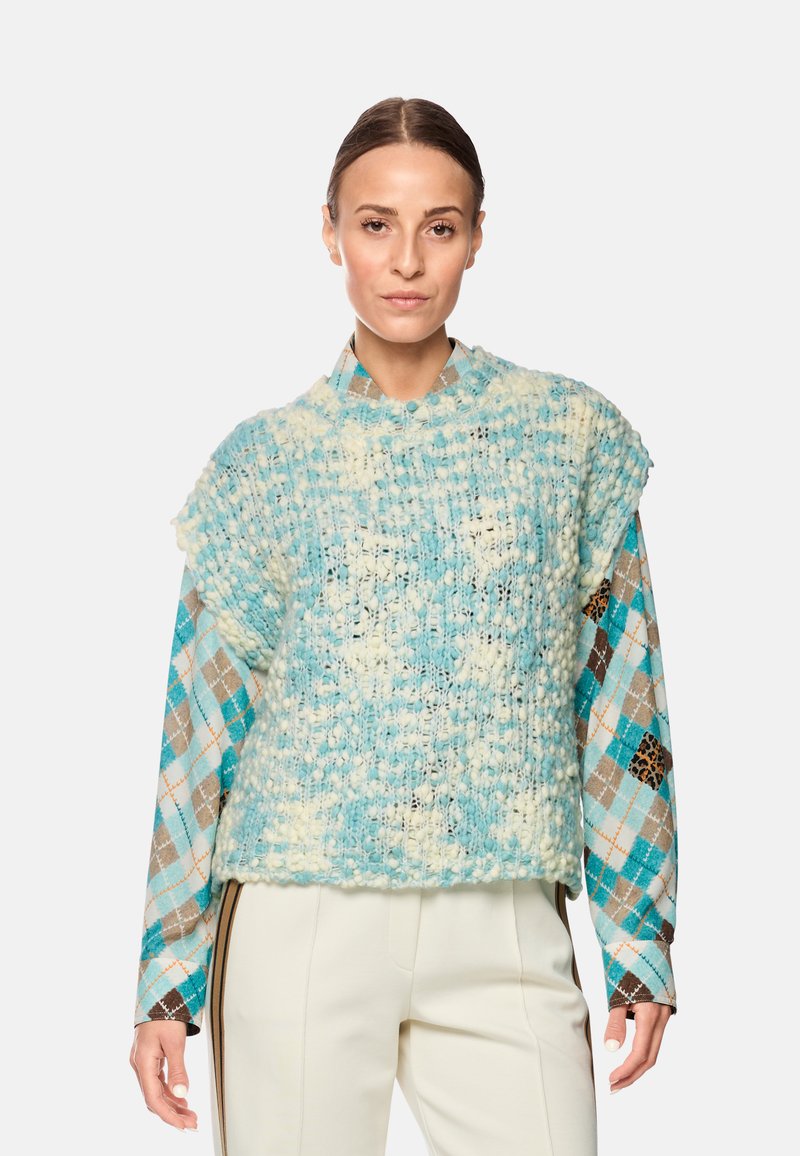 Knitted pullover in light blue and cream, featuring a textured design. Long sleeves display a checkered pattern in blue, brown, and tan.