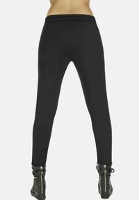 Czarne legginsy o dopasowanym kroju, elastycznym pasie i gładkiej fakturze, w połączeniu z czarnymi botkami za kostkę z zamkami.