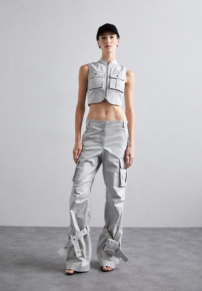 Gray cropped vest with two front pockets, paired with loose gray cargo pants featuring snap closures and wide legs. Model wears a black cap.