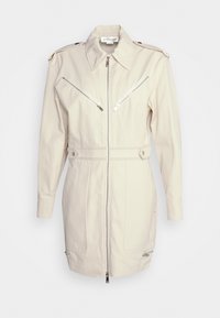 Světle béžová bunda s límcem, předním zipem a dvěma šikmými kapsami na zip. Vyrobena z texturované tkaniny s ramenními epauletami.