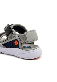 Sandale grise et marine offrant un mesh respirant, des sangles réglables, une semelle rembourrée et une semelle en caoutchouc avec un accent orange prononcé.