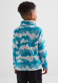 Turquoise fleece jacket with a mountain pattern in light blue and white. Low collar and long sleeves. Soft texture and casual fit.