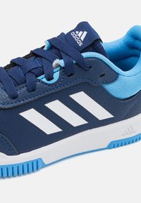 Baskets de sport bleu marine avec tige en cuir texturé et accents en mesh bleu clair. Présente un logo à trois bandes blanches et une semelle en caoutchouc bleu.