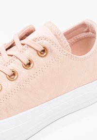 Baskets en daim rose clair avec semelle en caoutchouc blanche, lacets roses assortis passés dans des œillets dorés, et col rembourré.