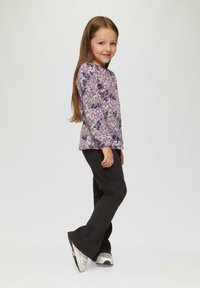 Langärmliges lila Oberteil mit floralem Muster, kombiniert mit dunklen Hosen und Sneakern. Es hat einen lässigen Schnitt und ein Rundhalsdesign.