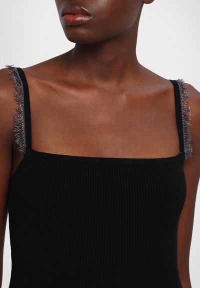 Débardeur noir à côtes avec des fines bretelles. Les bretelles présentent des accents argentés effilochés. La vue rapprochée met en avant une texture lisse et un décolleté carré.