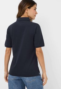 Marine polo shirt med krave, korte ærmer og lige kant. Fremstillet af blødt stof med en glat tekstur. Rent design, ingen synlige mønstre.