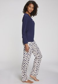 Navy long-sleeve top with round neckline paired with light pants featuring a navy abstract pattern. Both made from soft, breathable fabric.