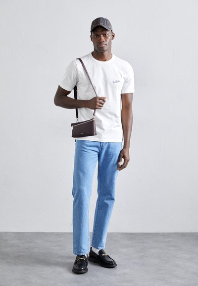 Valge lühikeste varrukatega T-särk, millel on broderi logo, helesinised teksad, mustad kingad kuldse aktsendiga ja triibuline müts. Pruun crossbody kott.