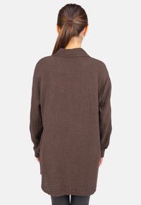Brown, textured button-up shirt with long sleeves and a soft, crinkled fabric, featuring a collar and an elongated back hem.