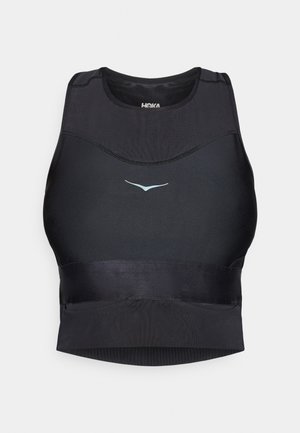 Czarny stanik sportowy z gładkiego, elastycznego materiału, o eleganckim designie i odblaskowym logo na froncie. Bez fiszbin, w kroju sportowym.