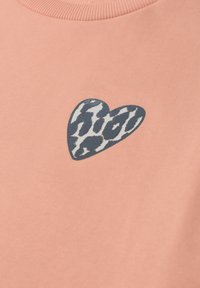 Tissu rose doux avec un petit patch en forme de cœur à imprimé léopard près du centre supérieur.