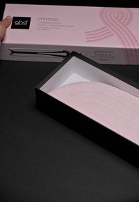 Svart och rosa förpackning för GHD Chronos hårstyler, med en glansig svart låda och en mjuk rosa matta inuti, som visar produktens design.