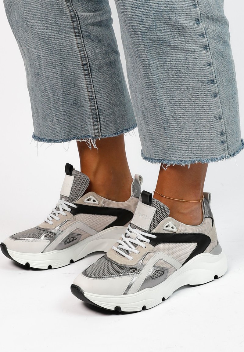 Chunky sneakers with mesh and synthetic textures, featuring a mix of gray, black, and white. Laces and a padded collar for comfort.