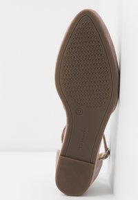 Semelle d'une chaussure beige à bout pointu avec une semelle antidérapante texturée, taille 37, et un petit talon bloc reposant sur un fond blanc.