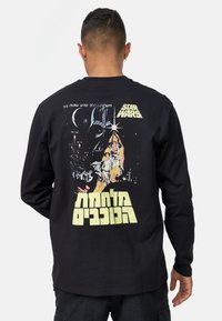Svart långärmad t-shirt med en livfull "Star Wars"-grafik på baksidan, med karaktärer mot en rymdbakgrund i olika färger.