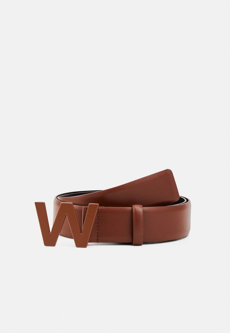 Ceinture en cuir brun enroulée à plat avec une grande boucle en métal brun en forme de la lettre « W » sur fond blanc.