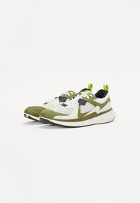 Nachhaltige Sneakers mit einer Kombination aus grünem Wildleder und Mesh-Obermaterial, weißen Akzenten, reflektierenden Details und einer schwarzen Gummisohle.