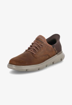Zapatilla de cuero marrón con la puntera redondeada, acentos texturizados, cordones marrones y una suela de goma gris acolchada con orificios de aire redondeados.